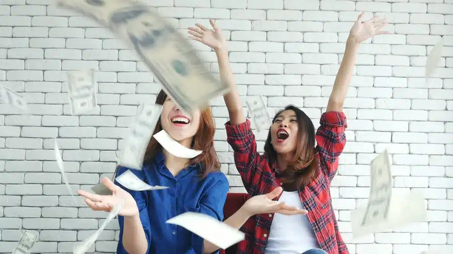 Two friends throwing cash from refer a friend program